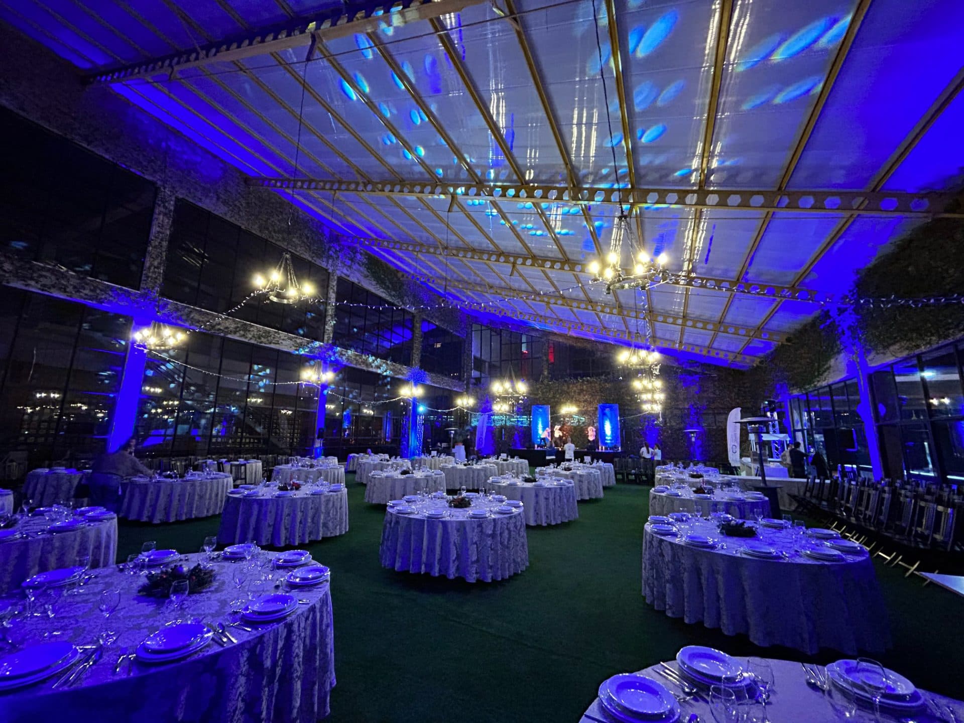 Segunda sala montada com mesas redondas sob iluminação quente